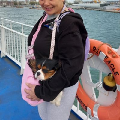 Femme sur un bateau avec son chien dans un sac de transport rose