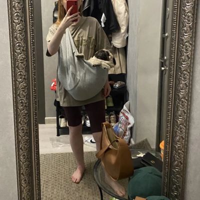 Femme prend un selfie devant un miroir avec son chien ans un sac de transport gris